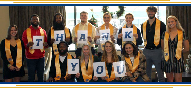 Student athletes spelling thank you in letter cards